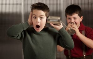 Image of two boys using a phone made of tin cans to be heard through
